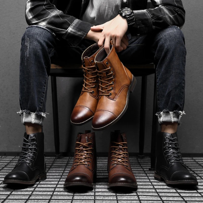 Man holding tan leather boots beside black and brown pairs
