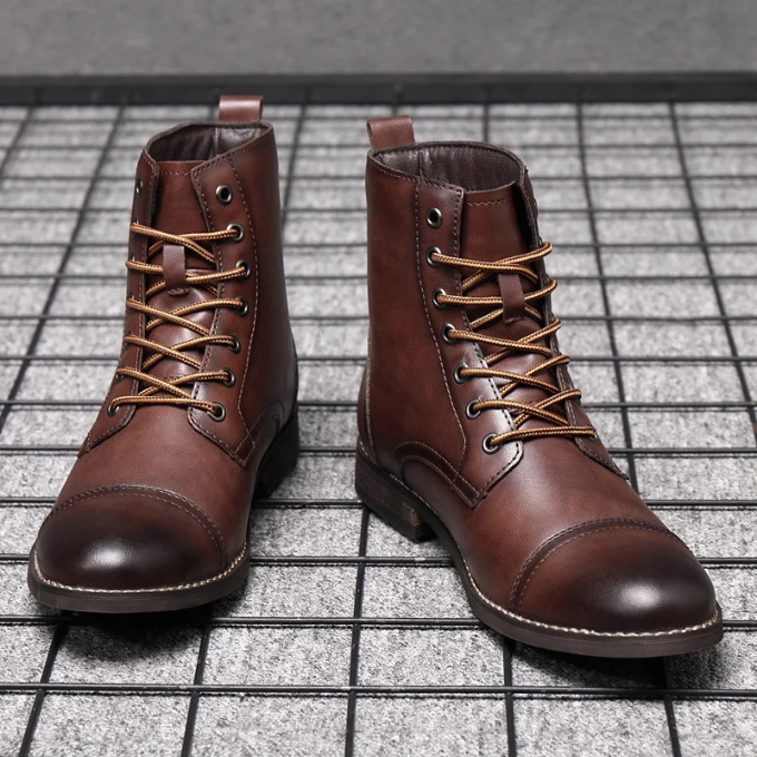 Front view of brown leather cap-toe boots on grid flooring