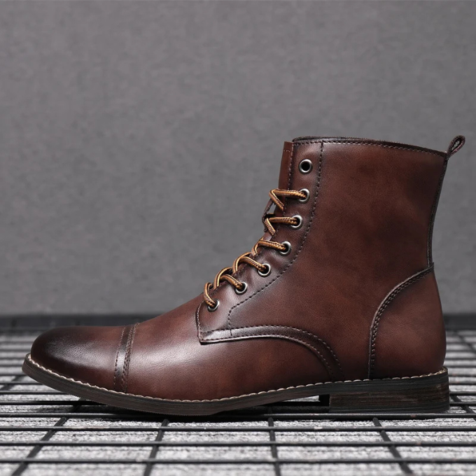 Brown leather men's boot with contrast stitching, shown against grid flooring