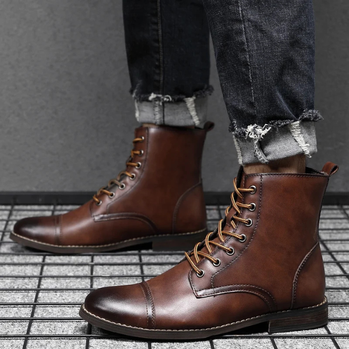 Close-up of tan leather boots worn with rolled-up denim jeans