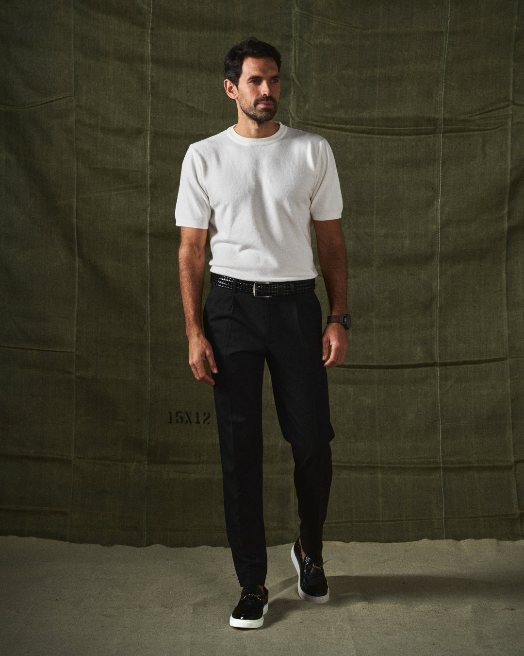 Man in white t-shirt and black trousers walking in black leather loafers