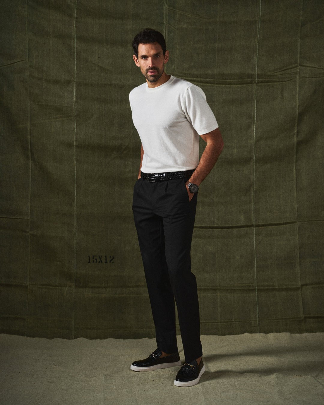 Man posing in white knit top and black trousers with black leather loafers