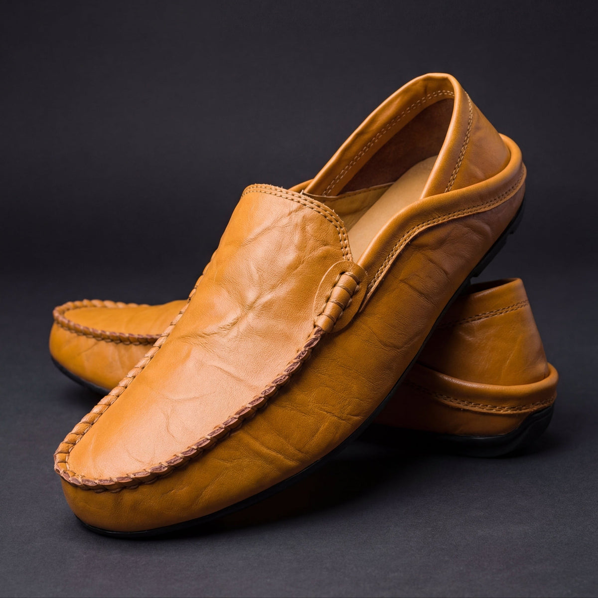 Pair of tan leather moccasins with woven strap detail and stitched edging