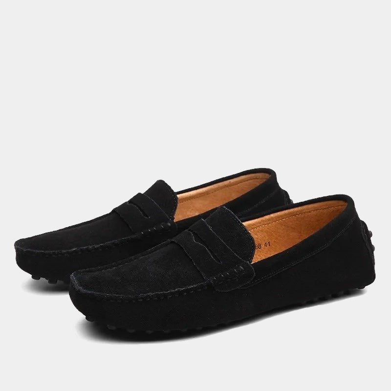 Black suede slip-on loafers with tan interior and studded driving sole